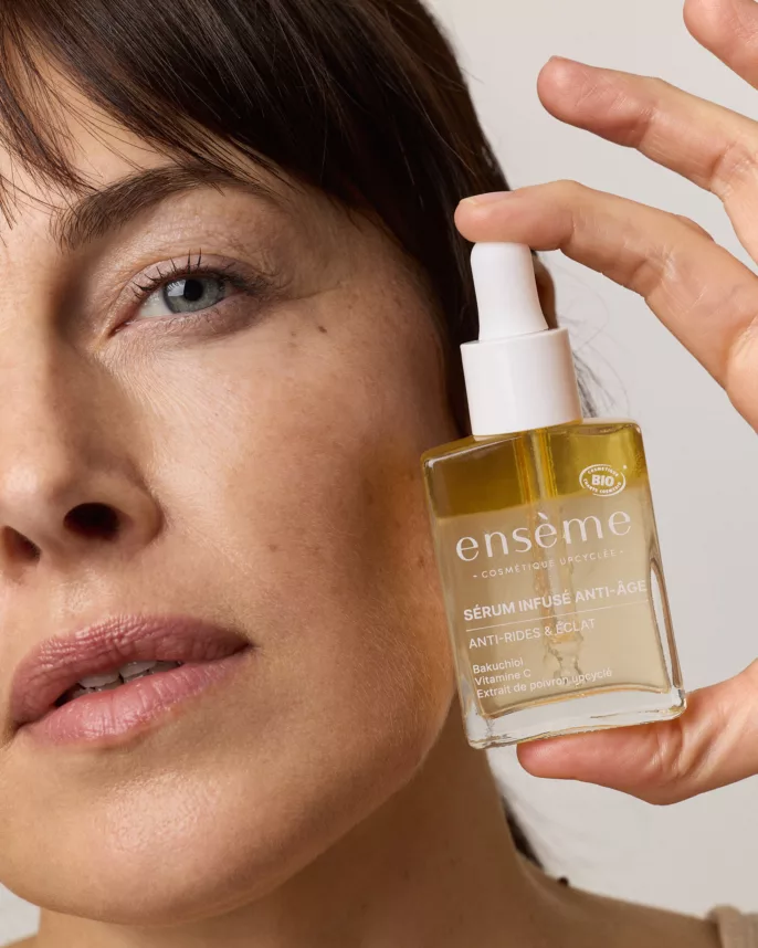 Portrait de femme mature tenant un flacon de sérum anti-âge ensème – cosmétique upcyclée à base de bakuchiol et vitamine C, photo beauté à Lyon.