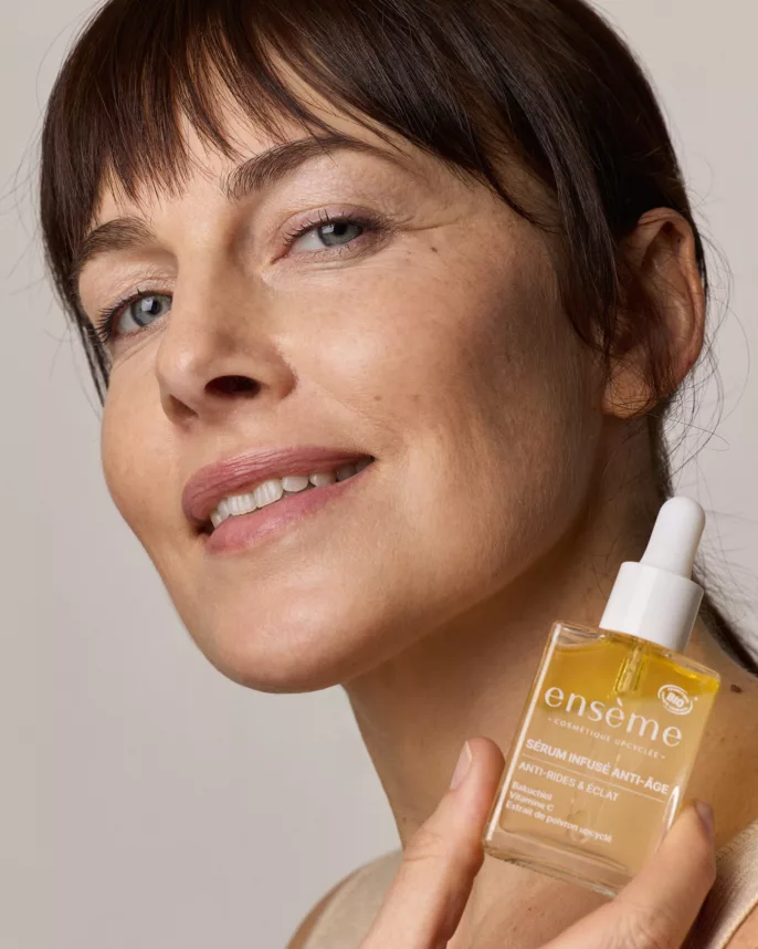 Portrait beauté d’une femme mature souriante tenant un sérum anti-âge de la marque Ensème, capturé par une photographe professionnelle à Lyon.