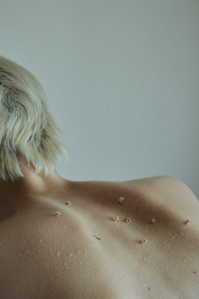 Photographie artistique d’un dos nu orné de pétales secs — ambiance minimaliste et poétique réalisée par un photographe beauté à Lyon.