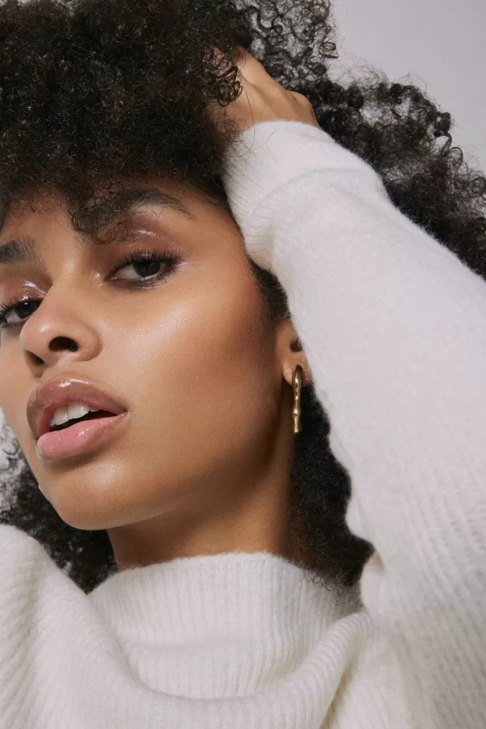 Portrait beauté d’une femme en studio, lumière douce et mise en valeur naturelle de la peau et de la boucle d’oreille.