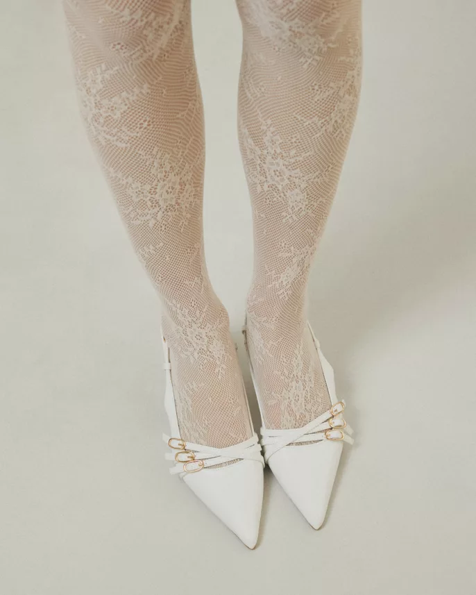 Photographie de mode à Lyon montrant des collants en dentelle blanche et des escarpins blancs à détails dorés.