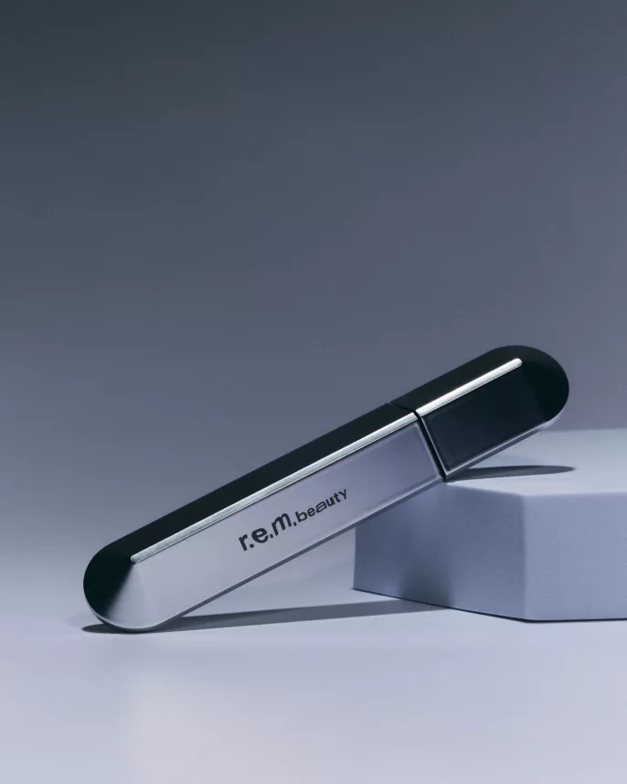 Photographie produit studio à Lyon d’un mascara r.e.m. beauty sur fond minimaliste gris.