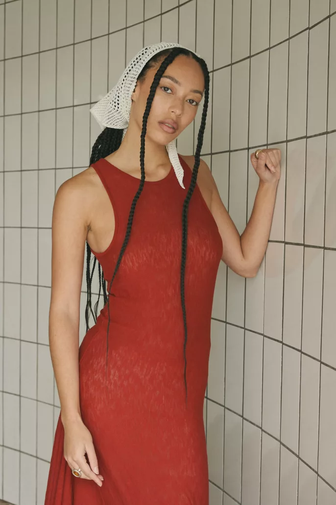 Femme en robe rouge et fichu blanc posant contre un mur carrelé – Portrait éditorial à Lyon