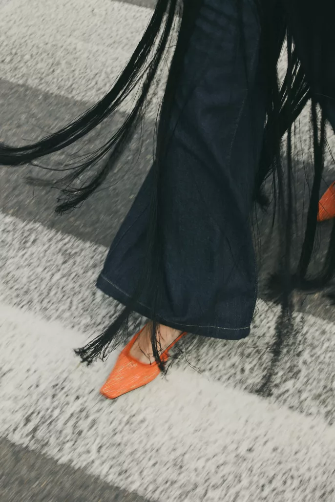 Gros plan sur une chaussure orange et un pantalon en jean avec franges en mouvement – Photographe mode Lyon