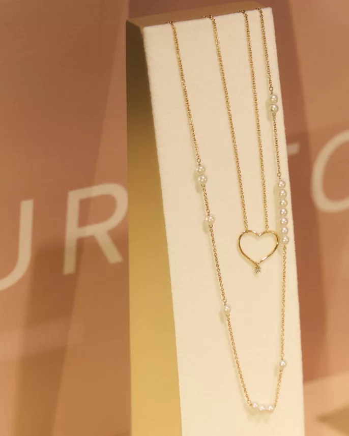 Photographie produit bijoux – collier en or avec perles et pendentif cœur présenté en vitrine