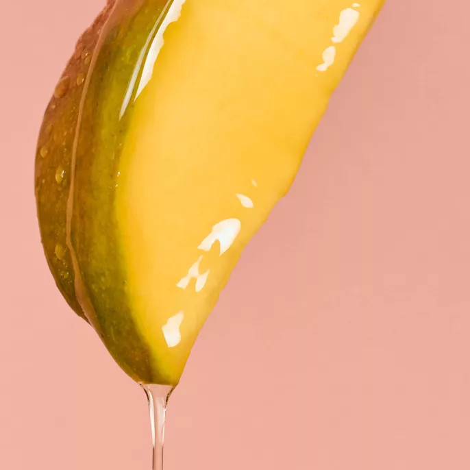 Tranche de mangue nappée de sérum qui s'écoule sur fond rose — shooting cosmétique Lyon, Stéphanie Lorang