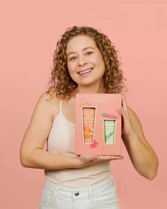 Fondatrice de La Belle Boucle tenant le coffret lait capillaire sur fond rose — portrait beauté Lyon, Stéphanie Lorang