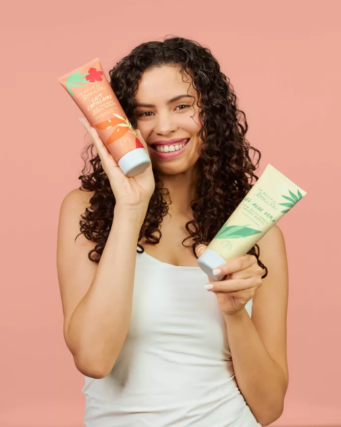 Modèle aux cheveux bouclés tenant le lait capillaire et le gel aloe vera La Belle Boucle — shooting beauté Lyon, Stéphanie Lorang