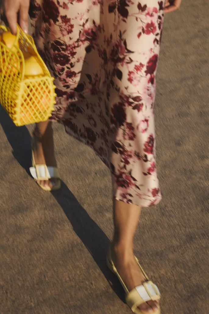 Photographie lookbook chaussures – sandales portées en mouvement avec robe fleurie en extérieur