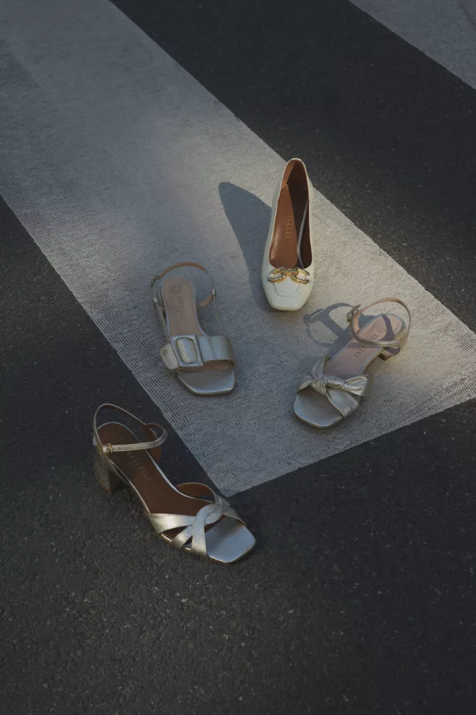 Photographie lookbook chaussures – sélection de sandales et escarpins disposés sur passage piéton en extérieur