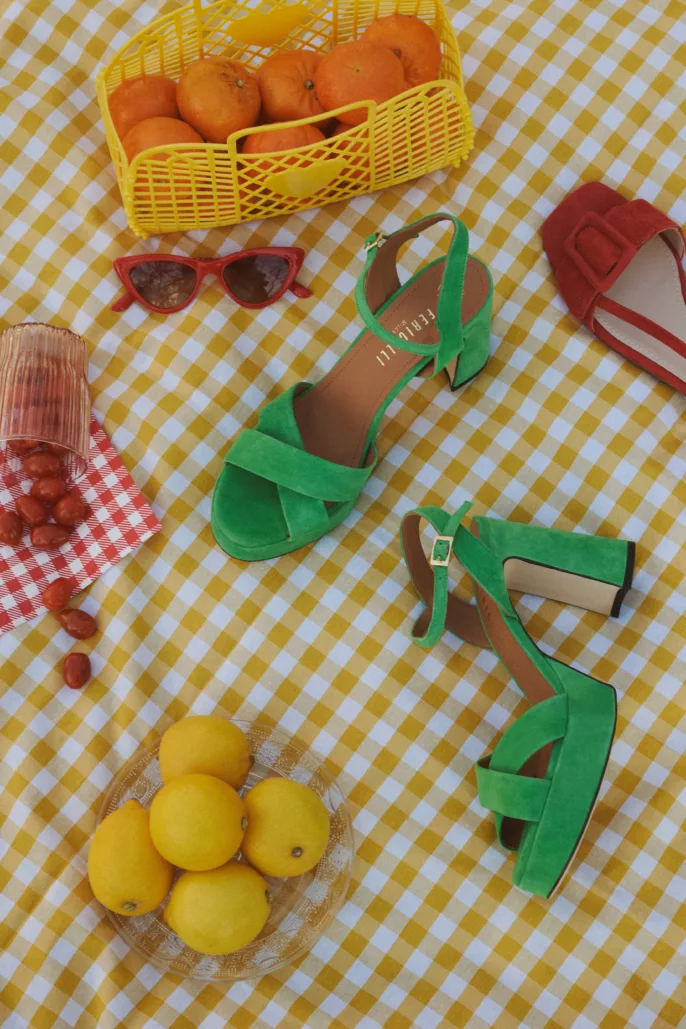 Photographie lookbook chaussures – sandales vertes mises en scène sur nappe à carreaux avec accessoires estivaux