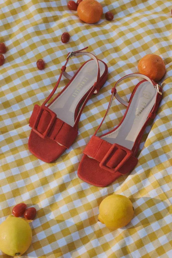 Photographie lookbook chaussures – sandales rouges mises en scène sur nappe à carreaux avec fruits