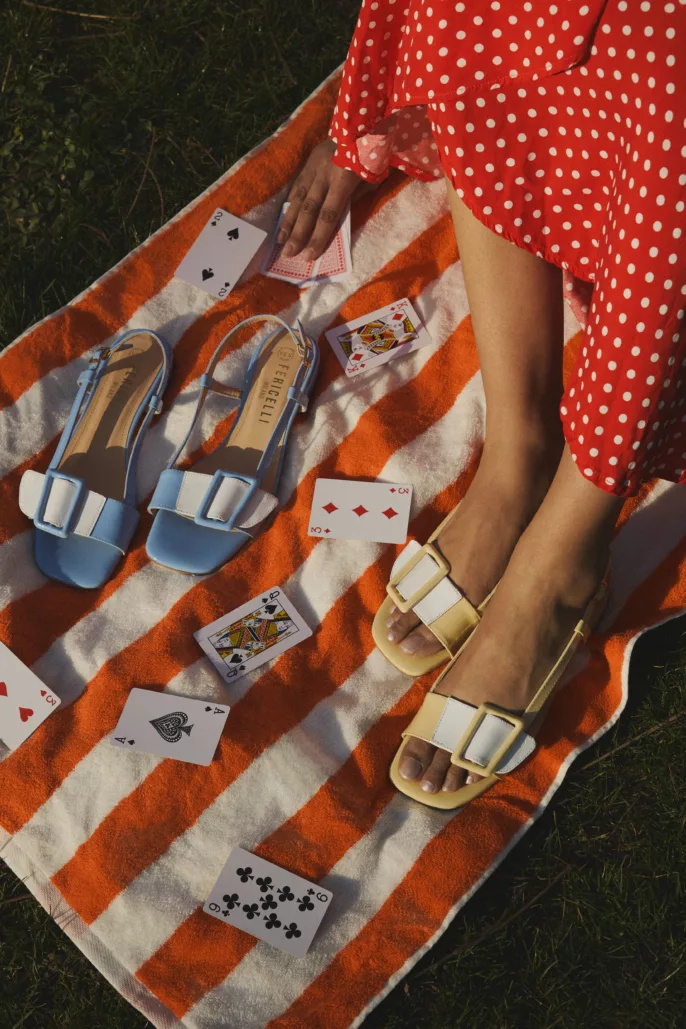 Photographie lookbook chaussures – sandales portées sur serviette rayée avec mise en scène estivale en extérieur