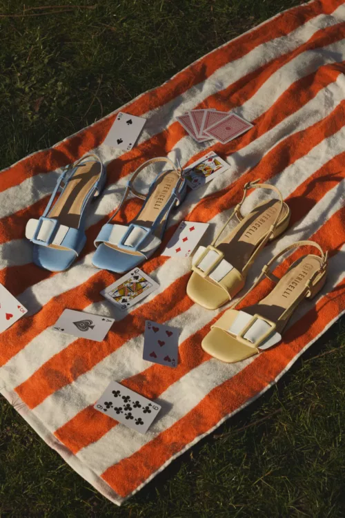 Photographie lookbook chaussures – sandales colorées mises en scène sur serviette rayée en extérieur