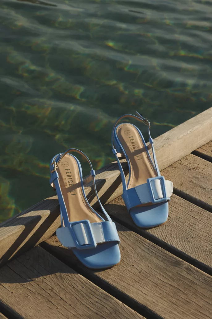 Photographie lookbook chaussures – sandales bleues posées sur ponton en bois au bord de l’eau