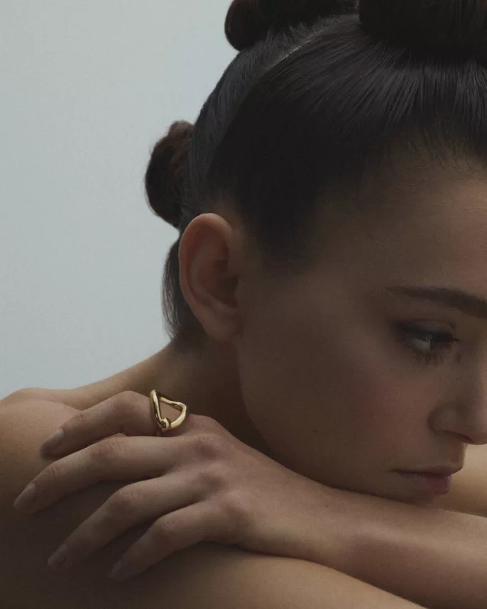 Modèle aux yeux baissés portant une bague dorée organique sur épaule — portrait bijoux éditorial Lyon, Stéphanie Lorang