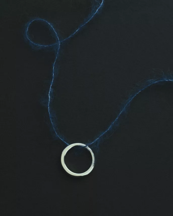 Anneau argent fin posé sur fil de laine bleu indigo sur fond noir — photographie bijoux éditorial Lyon, Stéphanie Lorang