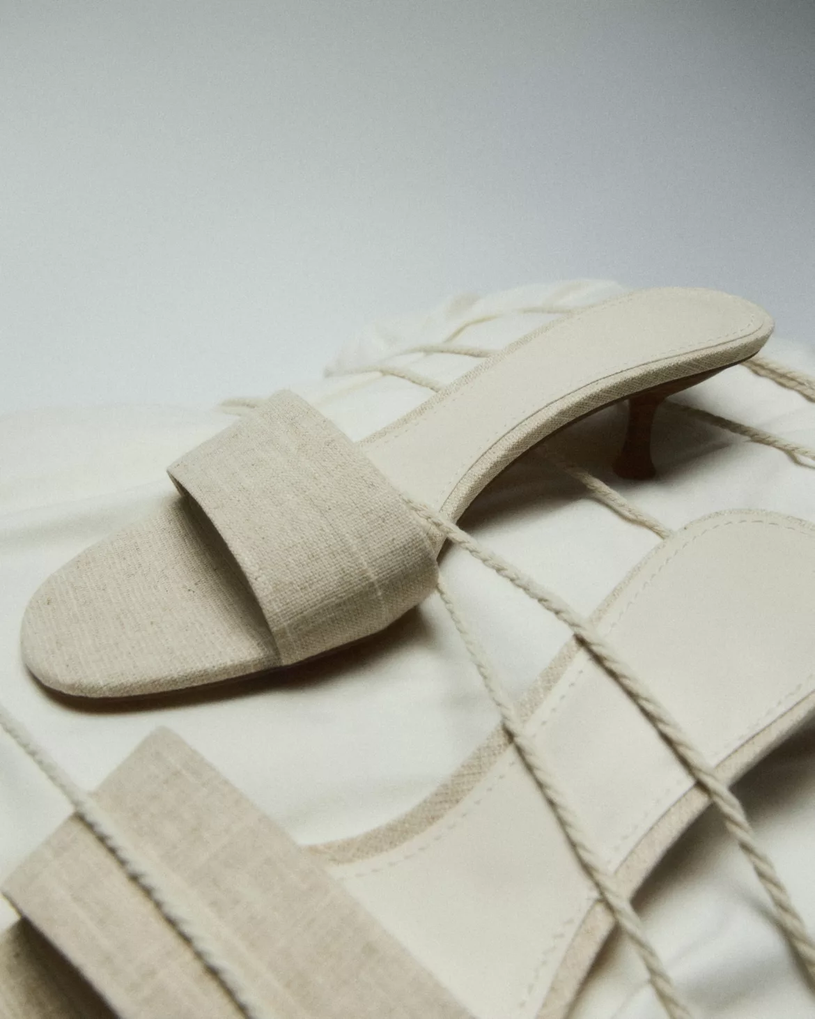 Mules à lanières en lin crème sur tissu froissé — photographie éditoriale mode studio Lyon, Stéphanie Lorang
