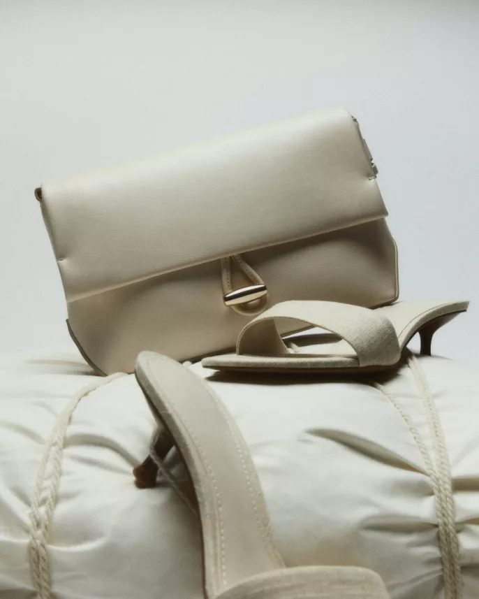 Mules en lin et sac pochette crème empilés sur oreiller gonflé — photographie éditoriale mode studio Lyon, Stéphanie Lorang