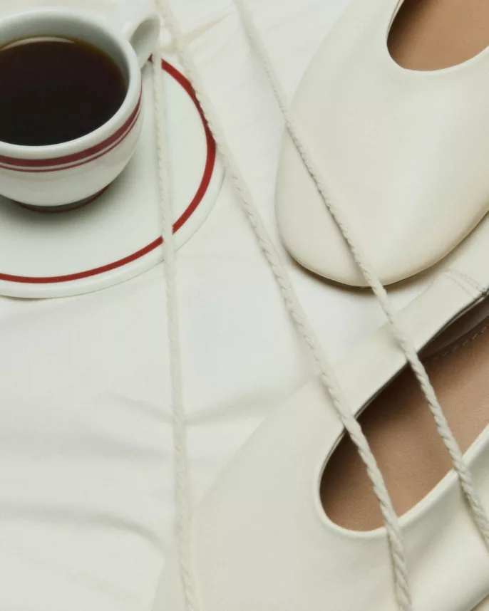 Chaussure à lacets crème et tasse de café à liseré rouge sur tissu blanc — photographie éditoriale mode Lyon, Stéphanie Lorang